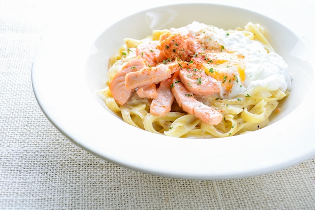 Fettucine au saumon, oeuf et parmesan, servis sur assiette blanche.