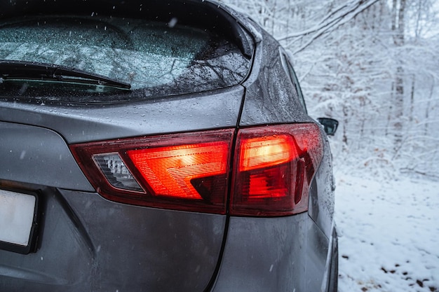 Le feu arrière de la voiture est en gros plan en arrière-plan de la forêt d'hiver