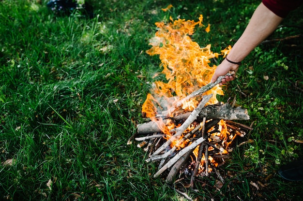 Photo feu de camp sur la nature. la branche est entre les mains de l'homme