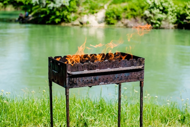 Feu dans le grill au bord de la rivière