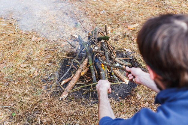 Feu de joie dans la forêt de printemps sur fond d'herbe desséchée Dans le cadre tête épaule et bras d'un homme