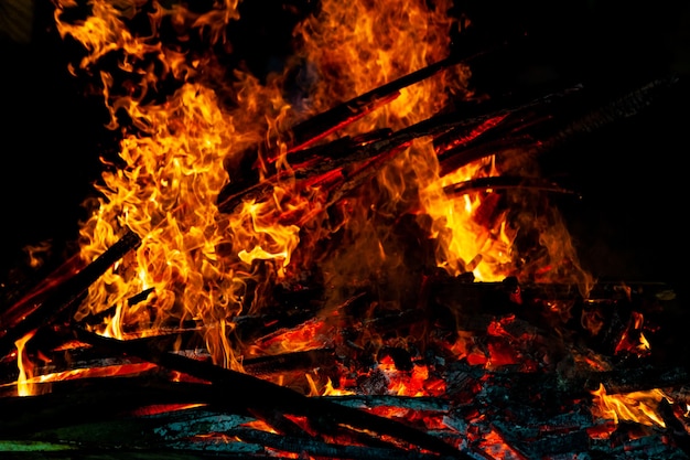 Feu de joie qui brûle sur un fond sombre, flamme au bois.