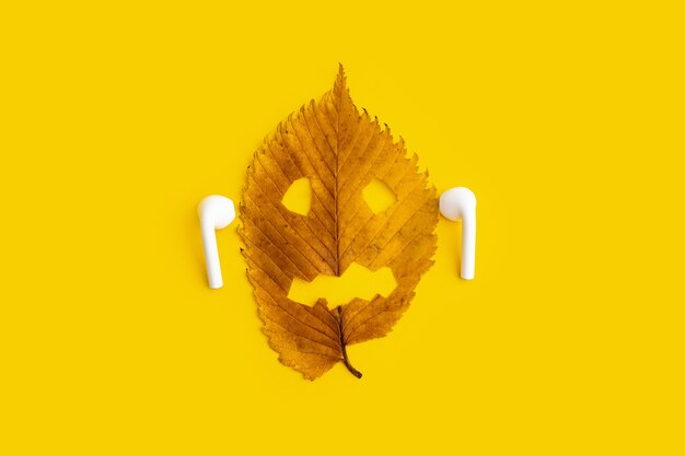 Feuille d'automne jaune avec visage d'halloween isolé sur fond blanc.