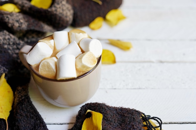 Feuille d'automne avec une tasse de café, écharpe, feuilles jaunes sur bois blanc