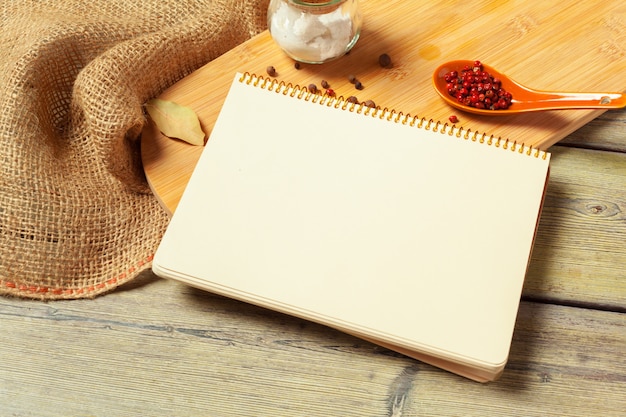 Feuille blanche de bloc-notes ouvert et d'ustensiles de cuisine sur une table avec une nappe