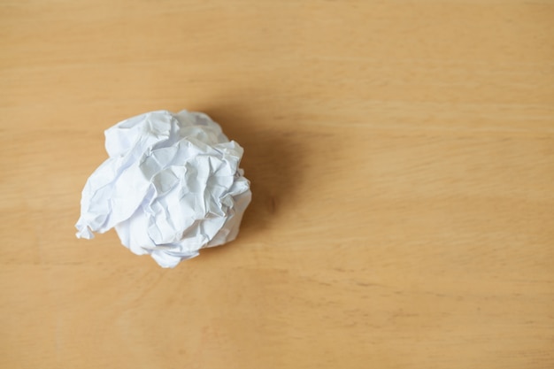 feuille blanche de boule de papier froissé grumeleux sur fond de plancher en bois