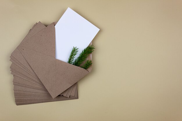 Une feuille blanche et propre dans une enveloppe brune avec un brin d'épinette. Maquette d'invitation et carte de voeux.