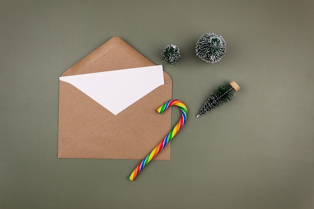 Une feuille blanche vierge dans une enveloppe artisanale à côté de petits arbres de Noël. Maquette d'invitation et carte de voeux. Le style est le minimalisme moderne. Vue de dessus, mise à plat.