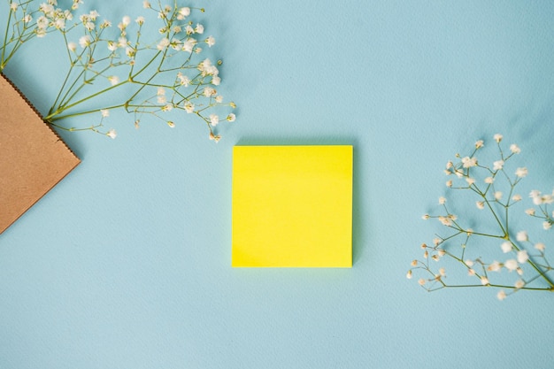 Une feuille carrée propre sur une table bleue avec vue de dessus de fleurs blanches Place pour le texte