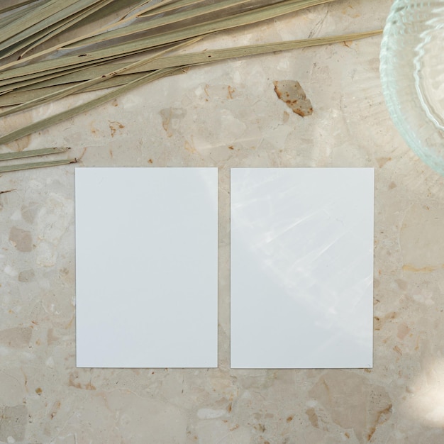 Feuille de carte en papier avec maquette blanche espace de copie vase en verre de feuille de palmier séché sur fond de marbre silhouette d'ombre de lumière du soleil esthétique modèle d'invitation ou de carte de visite bohémienne de luxe