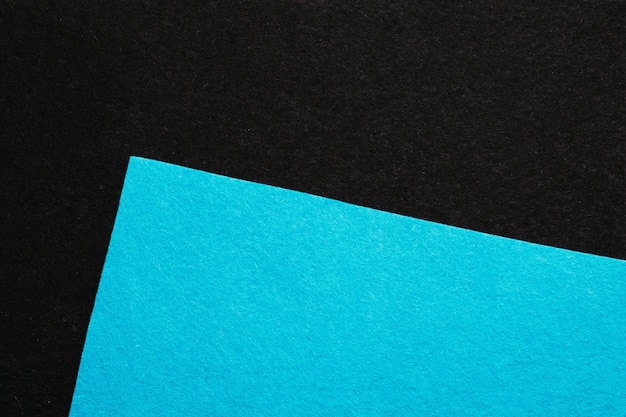 Feuille coudée de texture feutre bleu ciel sur collage géométrique minimaliste abstrait sombre