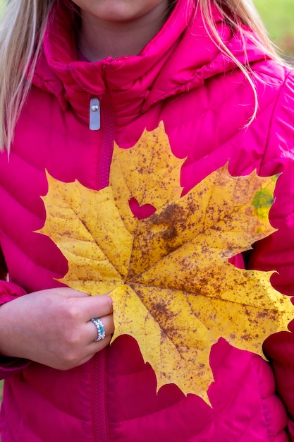 Feuille d'érable d'automne avec un coeur sculpté dans la main de la fille Concept de saison préféré