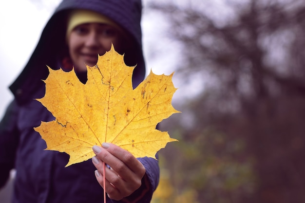 Feuille jaune d'automne dans les mains d'une fille