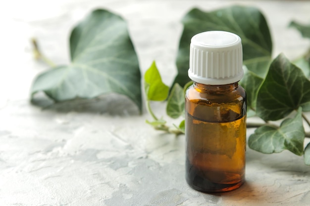 Une feuille de lierre et de sirop dans une bouteille sur une table en béton clair. Production de médicaments contre la toux avec extrait de lierre. industrie pharmaceutique