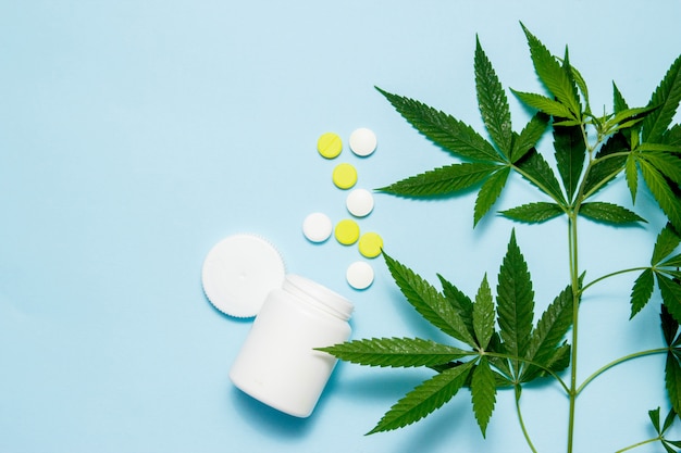 Photo feuille de marijuana avec des pilules médicales sur bleu.