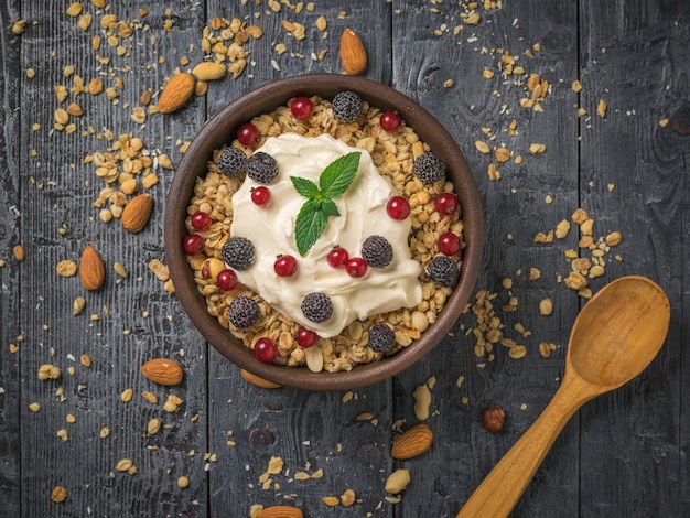 Une feuille de menthe dans une tasse de yaourt et de granola sur une table en bois