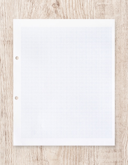 Feuille de papier blanc avec motif de lignes de quadrillage sur bois.