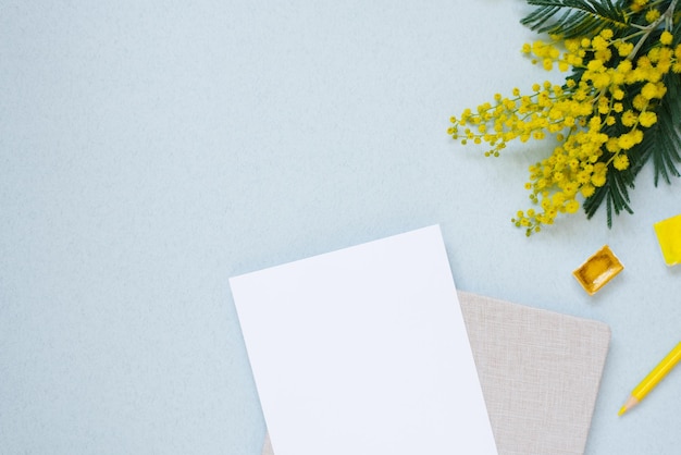 Feuille de papier blanche pour l'espace de copie entourée d'aquarelles au crayon jaune du bloc-notes mimosa printanier