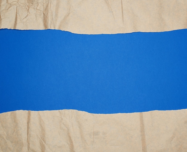 Feuille de papier brun déchiré sur fond bleu, plein cadre