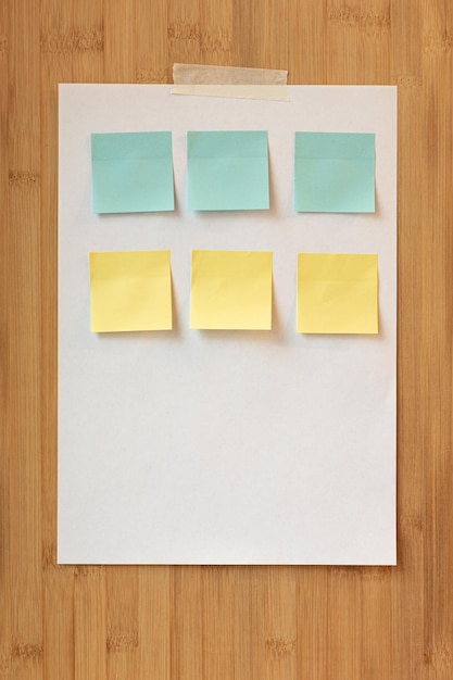 Une feuille de papier avec des post-it multicolores est accrochée à une planche de bois