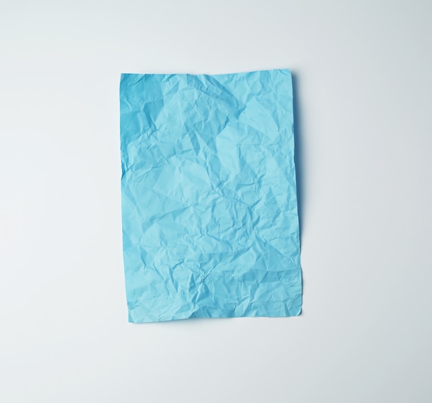 Feuille de papier rectangulaire bleu froissé vide sur une surface blanche