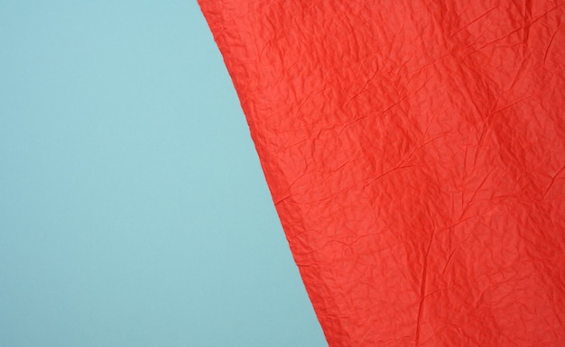 Feuille de papier rouge froissée sur fond bleu, plis et éraflures. Lieu d'inscription, plein cadre