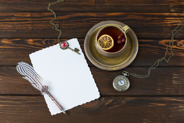 Photo une feuille de papier, un stylo-plume, une vieille montre de poche, une clé et une tasse de thé