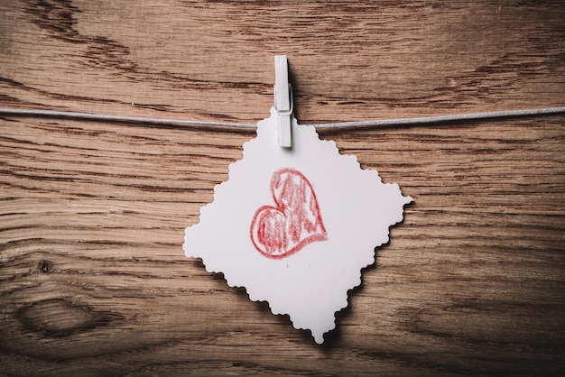 Feuille de papier vide vide et un coeur rouge sur un fond en bois