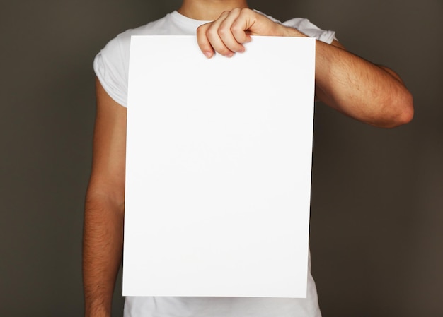 Feuille de papier vierge dans la main masculine sur fond sombre