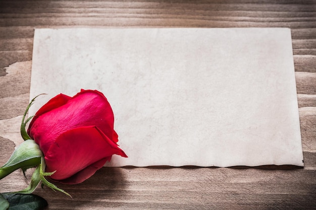 Feuille de papier vierge et rose fleurie sur planche de bois