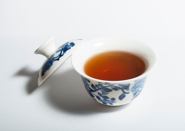 Feuille de thé oolong chinois sec et thé oolong dans une tasse traditionnelle sur du thé gaiwan blanc