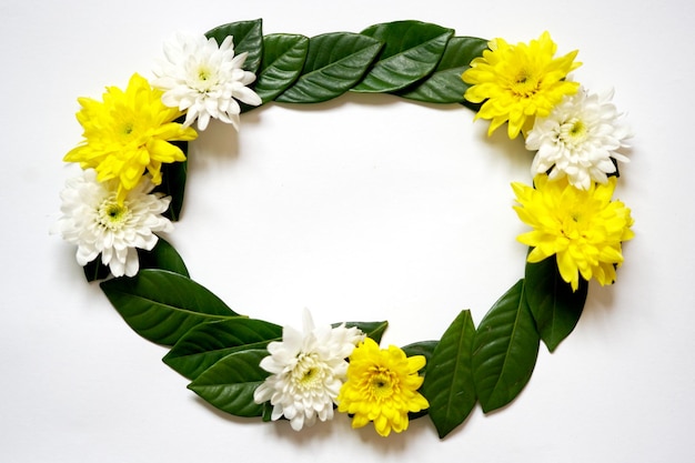 Feuille verte, cadre fleur blanc et jaune sur fond en bois