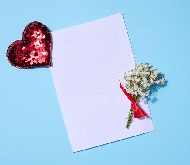 Feuille vide de bouquet de gypsophile en papier et coeur de sequin rouge sur fond bleu vue de dessus