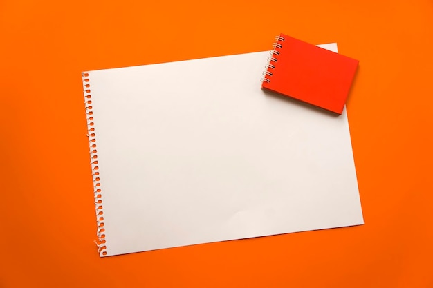 Feuille vierge d'espace papier pour la conception et le lettrage sur un beau fond orange Feuille de bloc-notes rouge Feuille perforée déchirée du bloc-notes obliquement allongé sur la surface Feuille de papier carrée