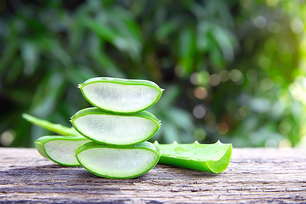 Feuilles d'aloe vera fraîches et des tranches sur une table en bois.