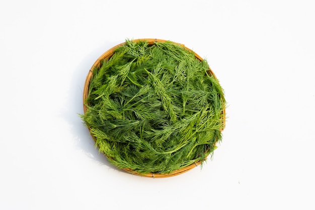 Feuilles d'aneth vert frais dans le panier sur une surface blanche