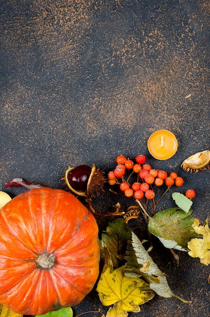 Feuilles d'automne, citrouille, châtaignes, bougies sur un fond sombre