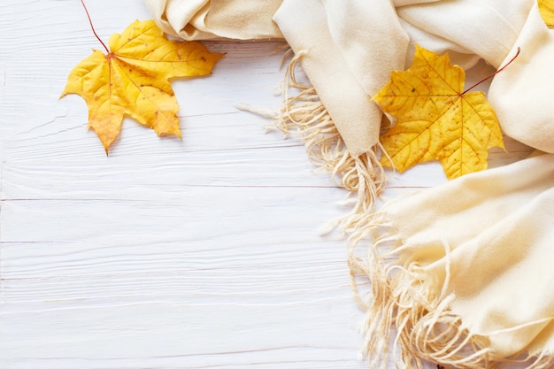 Feuilles d'automne avec une écharpe sur un fond en bois avec espace de copie