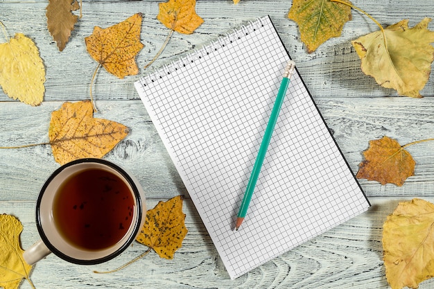 Feuilles D'automne Jaune, Une Tasse De Thé Et Un Cahier Sur Un Fond En Bois Ancien Clair