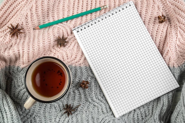Feuilles d'automne jaunes, une tasse de thé et un cahier sur un pull texturé