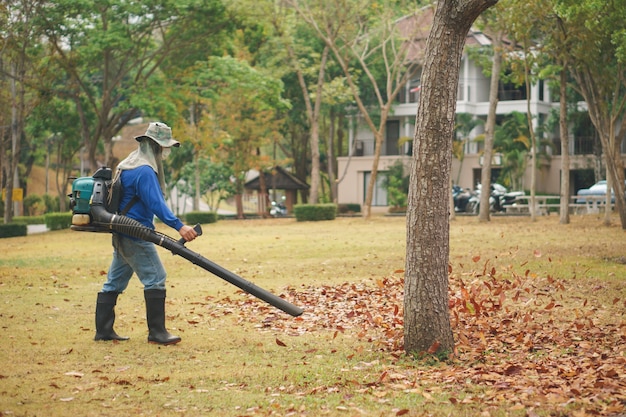 Feuilles d&#39;automne nettoyant par ouvrier avec souffleuse