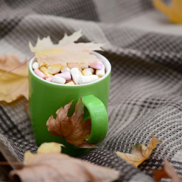 Photo les feuilles d'automne et la tasse de café chaude et fumante se trouvent sur des plaques à carreaux à l'extérieur.