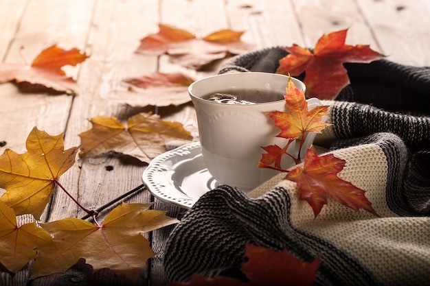 Photo feuilles d'automne et tasse de thé sur la table en bois.