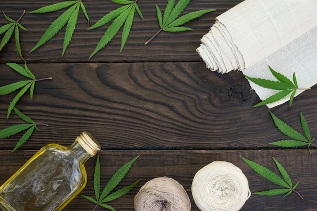 Photo feuilles de cannabis, une bouteille d'huile de chanvre et des enchevêtrements de fil sur une surface en bois sombre