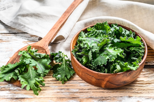 Feuilles de chou vert superfood frais dans un bol en bois. Nourriture végétarienne biologique. Fond blanc. Vue de dessus.