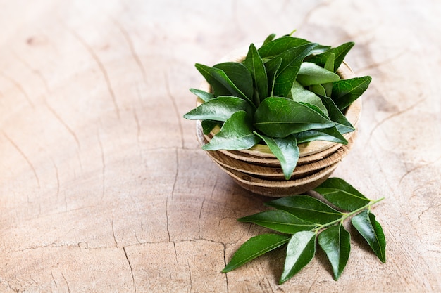 Feuilles De Curry Frais Dans Un Bol De Noix De Coco Sur Fond En Bois