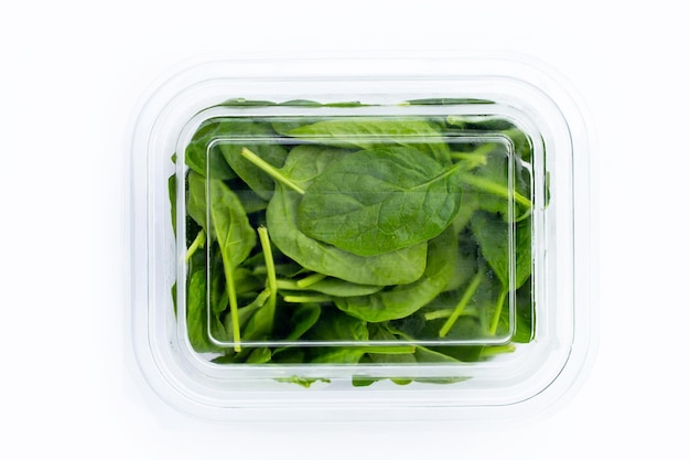 Feuilles d'épinards dans une boîte en plastique sur fond blanc