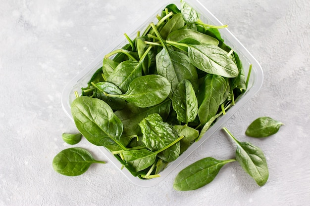 Feuilles d'épinards fraîches. Épinards crus pour salade végétarienne ou végétalienne ou smoothie sur fond de béton gris. Vue de dessus, copiez l'espace.