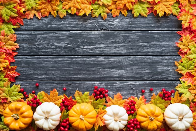 Feuilles d&#39;érable automne avec baies citrouille et rouge sur fond en bois ancien.