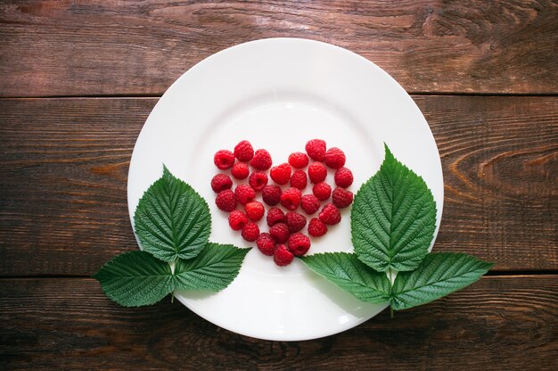 Feuilles en forme de coeur framboise sur table en bois plaque